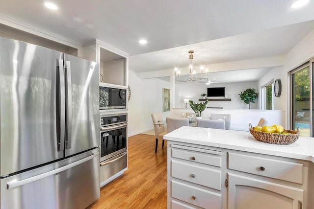 kitchen with an inviting chandelier, hanging light fixtures, stainless steel appliances, light hardwood / wood-style floors, and white cabinets