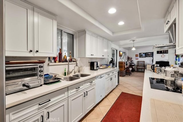 kitchen featuring white dishwasher, sink, white cabinetry, and a raised ceiling