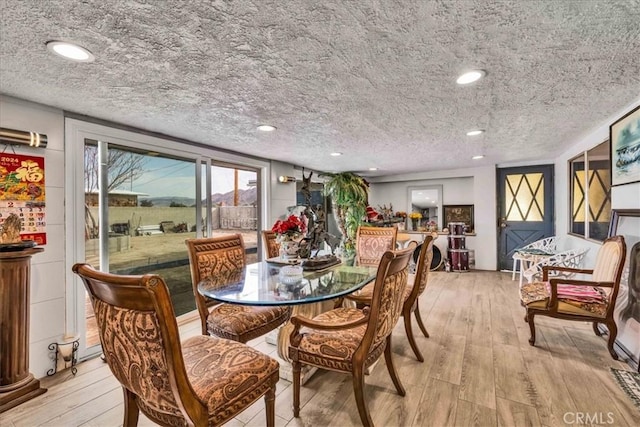 dining space with a textured ceiling and light wood-type flooring