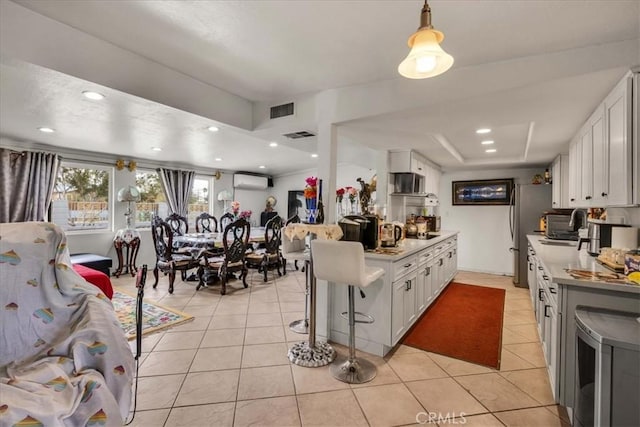 kitchen featuring white cabinetry, a kitchen breakfast bar, light tile patterned flooring, and an AC wall unit