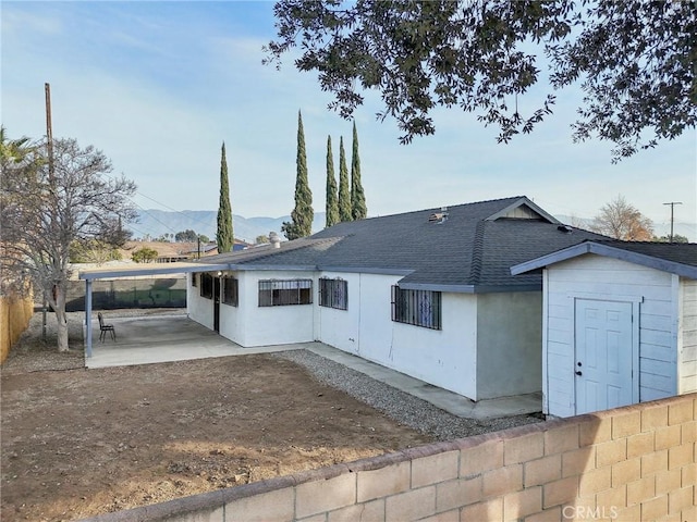 back of property with a mountain view, a patio area, and a shed