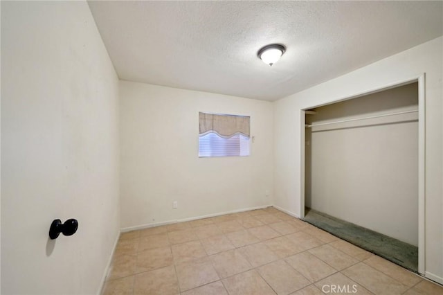 unfurnished bedroom featuring a closet, a textured ceiling, and light tile patterned floors