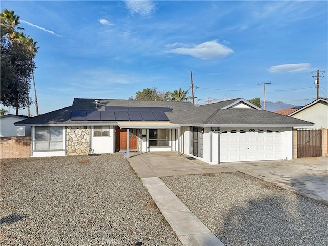 ranch-style house with a garage and solar panels