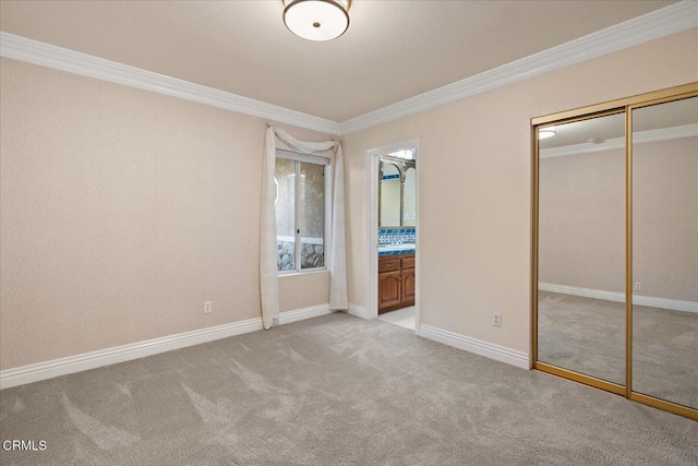 unfurnished bedroom with a closet, ornamental molding, ensuite bathroom, and light carpet