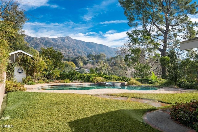 view of swimming pool featuring an in ground hot tub, a mountain view, and a lawn