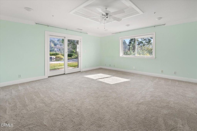 empty room featuring a raised ceiling, carpet floors, and ceiling fan