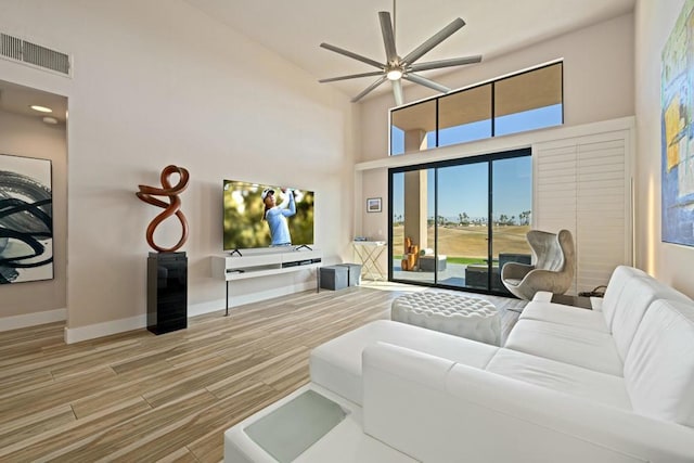 living room featuring hardwood / wood-style floors, a towering ceiling, and ceiling fan