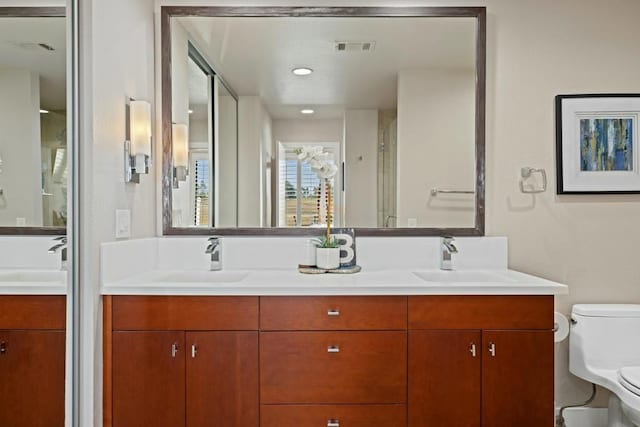 bathroom featuring vanity, a shower with shower door, and toilet