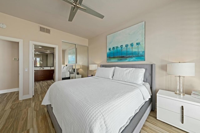 bedroom featuring connected bathroom, light hardwood / wood-style flooring, a closet, and ceiling fan