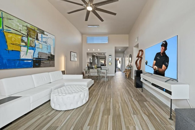 living room with hardwood / wood-style flooring, a high ceiling, and ceiling fan