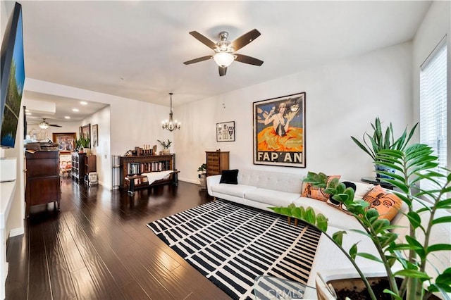 living room with ceiling fan with notable chandelier and dark hardwood / wood-style floors