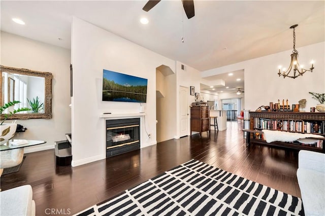 living room with dark wood-style floors, recessed lighting, visible vents, and a glass covered fireplace