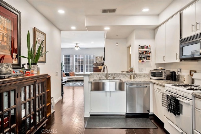 kitchen featuring light stone countertops, white cabinetry, white gas range, and stainless steel dishwasher