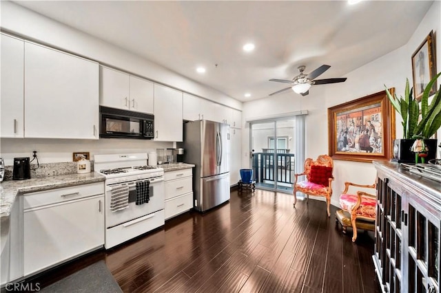 kitchen featuring black microwave, white range with gas stovetop, white cabinets, freestanding refrigerator, and light stone countertops