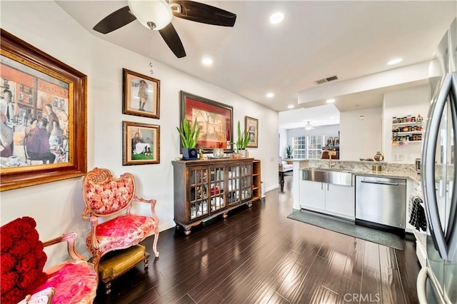 kitchen featuring stainless steel appliances, dark wood-style flooring, a sink, visible vents, and light stone countertops