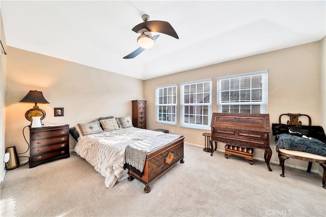 bedroom with a ceiling fan, light carpet, and baseboards