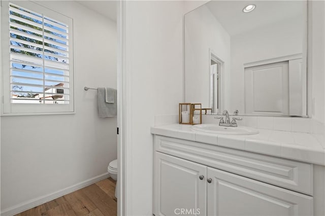 bathroom with wood-type flooring, toilet, and vanity