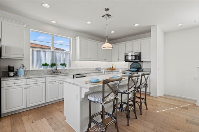 kitchen with white cabinetry, light wood-type flooring, a kitchen island, and pendant lighting