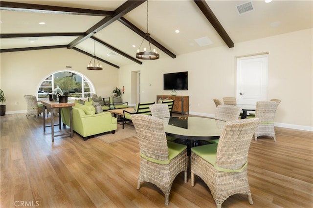 dining room featuring lofted ceiling with beams, a chandelier, and light hardwood / wood-style flooring