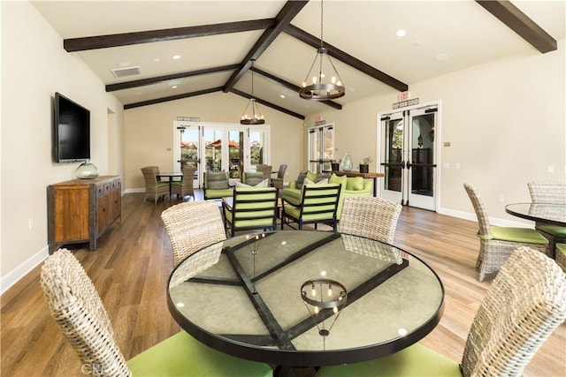 dining space with french doors, wood-type flooring, lofted ceiling with beams, and a notable chandelier