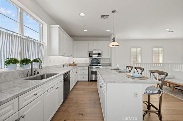 kitchen with white cabinetry, a center island, appliances with stainless steel finishes, and sink