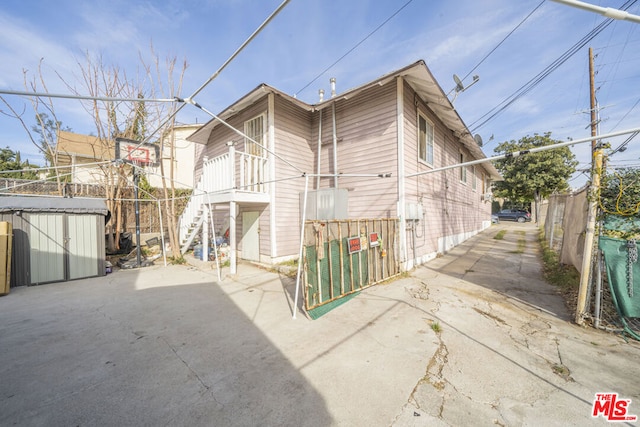 rear view of property featuring a patio area and a shed