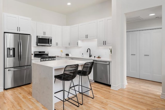 kitchen with a center island, appliances with stainless steel finishes, a breakfast bar, and white cabinets