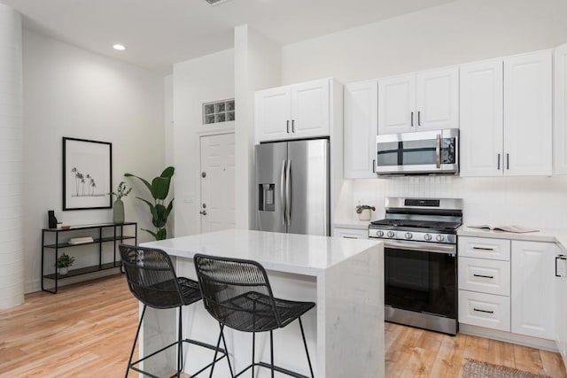 kitchen with a breakfast bar area, stainless steel appliances, a center island, and white cabinets