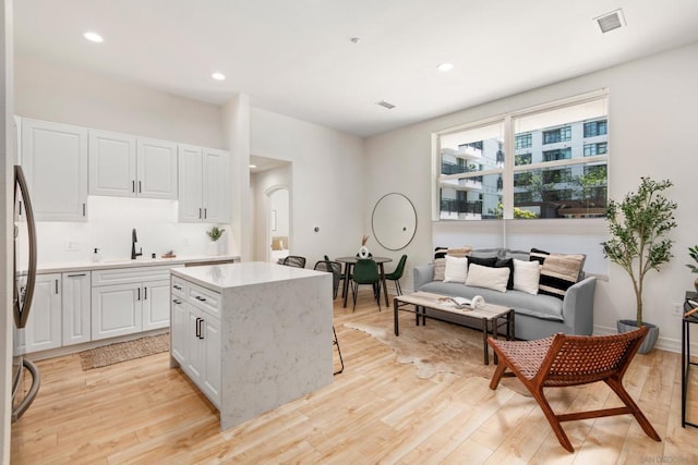 kitchen featuring a center island, sink, white cabinets, and light wood-type flooring