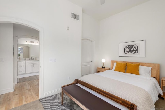 bedroom with ceiling fan, ensuite bath, sink, and light wood-type flooring