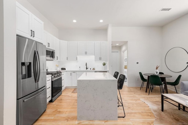 kitchen featuring white cabinetry, appliances with stainless steel finishes, and a breakfast bar