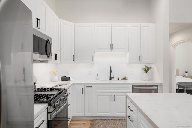 kitchen featuring white cabinetry, light stone counters, and appliances with stainless steel finishes