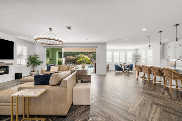 living room featuring a notable chandelier, dark parquet flooring, and sink