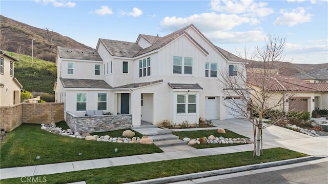 view of front of house featuring a garage, a mountain view, and a front lawn