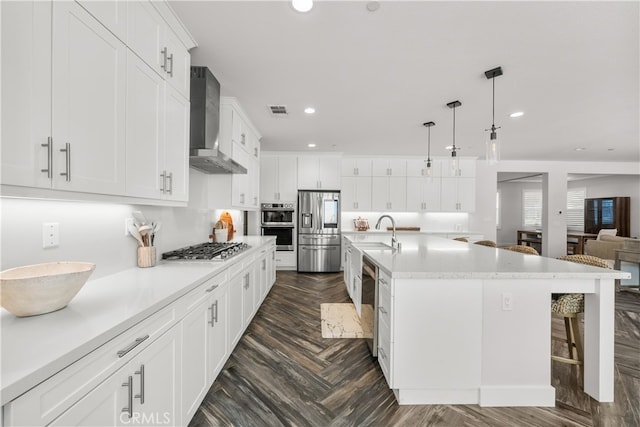 kitchen featuring white cabinets, hanging light fixtures, sink, and wall chimney exhaust hood