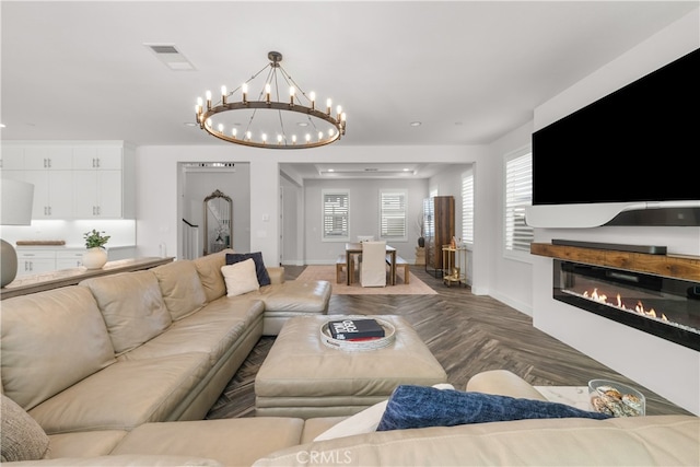 living room featuring an inviting chandelier and dark parquet floors