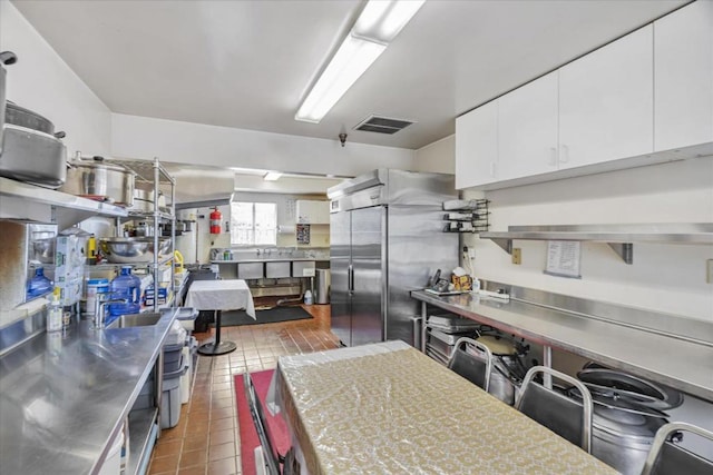 kitchen with white cabinetry, built in fridge, stainless steel counters, and dark tile patterned floors