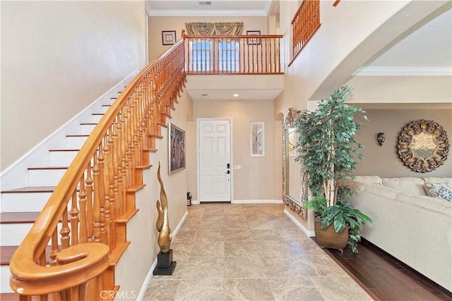 foyer featuring crown molding and a towering ceiling