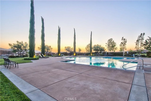 pool at dusk featuring a patio