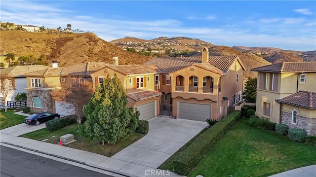 mediterranean / spanish house featuring a mountain view, a garage, and a front lawn