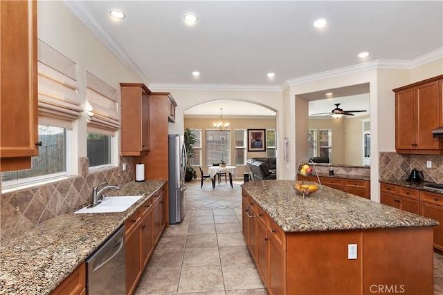 kitchen featuring appliances with stainless steel finishes, stone countertops, sink, decorative backsplash, and a center island