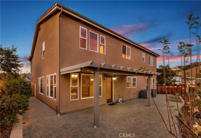 back house at dusk with a patio and cooling unit