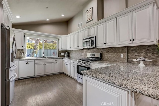 kitchen with lofted ceiling, sink, white cabinetry, stainless steel appliances, and light stone counters