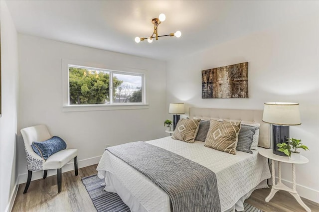 bedroom featuring wood-type flooring and a chandelier