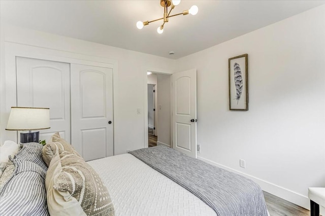 bedroom with hardwood / wood-style floors, a notable chandelier, and a closet