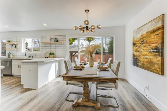 dining space featuring an inviting chandelier, sink, and light hardwood / wood-style floors