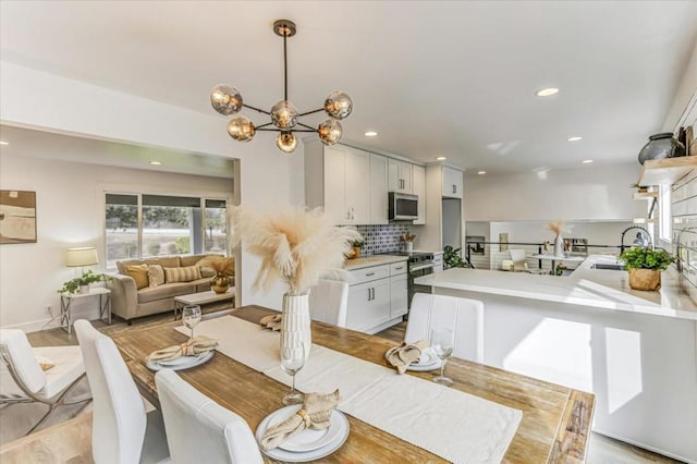 dining space featuring sink, light hardwood / wood-style flooring, and a chandelier