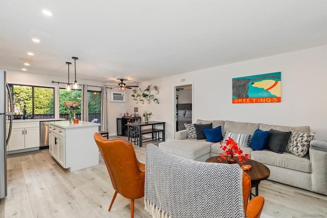 living room with light hardwood / wood-style floors, an AC wall unit, and ceiling fan