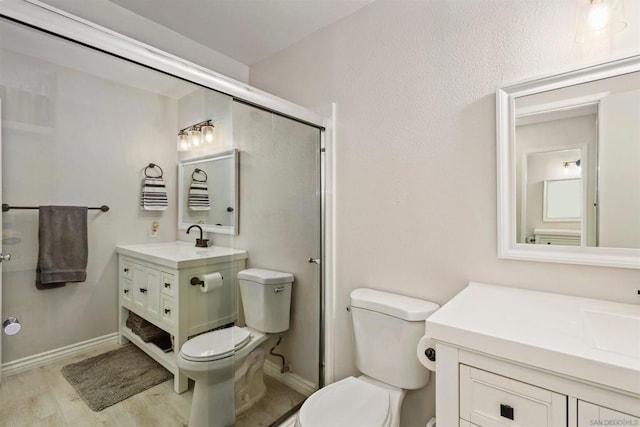 bathroom featuring hardwood / wood-style flooring, vanity, walk in shower, and toilet