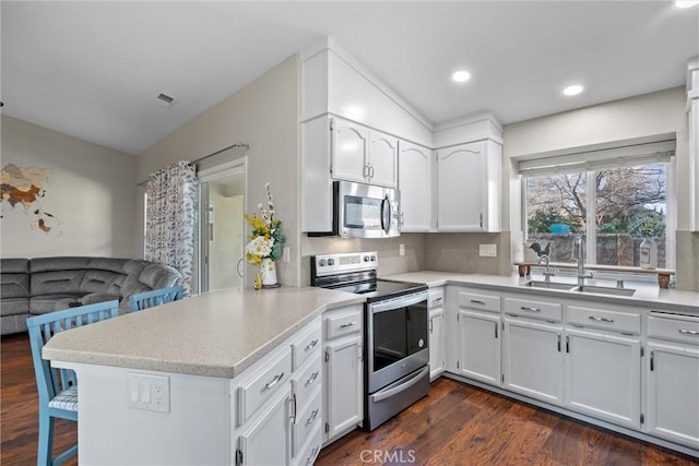 kitchen featuring sink, white cabinetry, stainless steel appliances, and kitchen peninsula